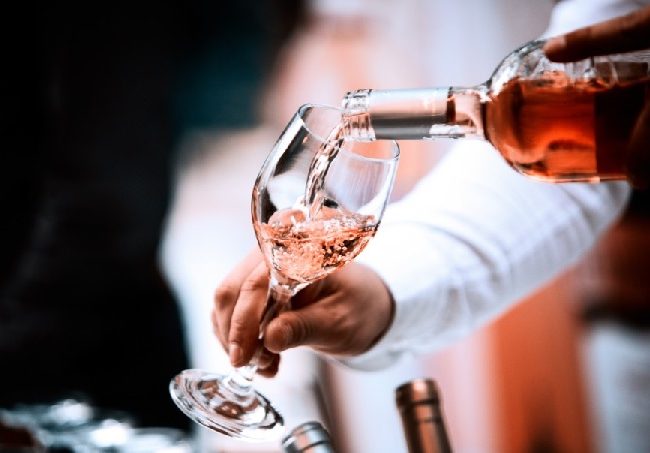 Pouring of rose wine into a tasting glass