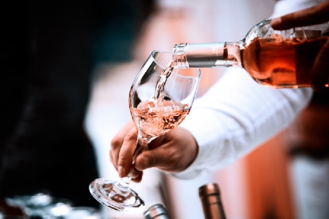 Pouring of rose wine into a tasting glass